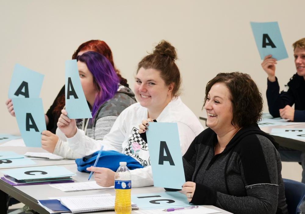 A group of students holding up signs with the letter "A" on them